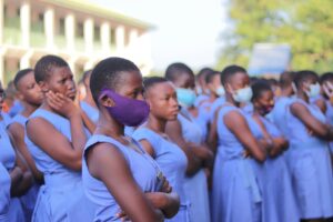 A group of students wearing blue uniforms and face masks gathered outdoors in Moyiri, Ghana.